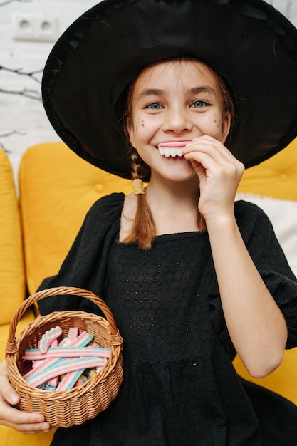 Griezelig Halloween-portret van een meisjesheks die een mand met traktaties houdt