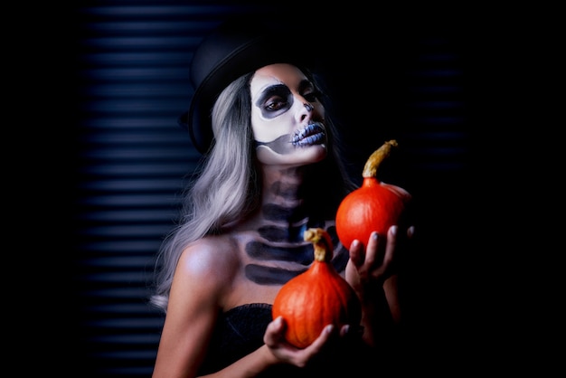 Griezelig portret van vrouw in halloween gotische make-up met pompoen