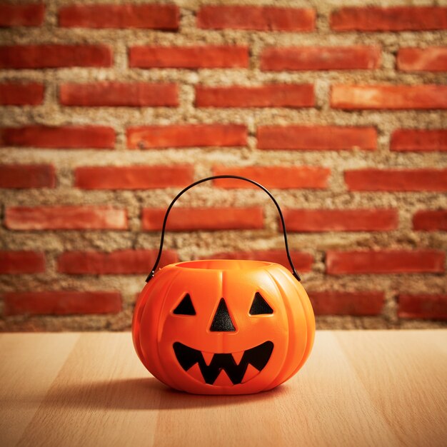 Griezelige Halloween-pompoen, Jack O Lantern op een houten banktafel en ruimte voor tekst op een bakstenen muur