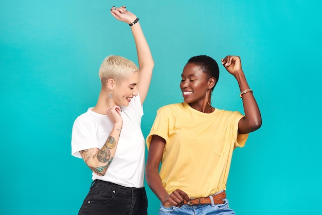 Grijp je meisje en ga grooven Studio-opname van twee jonge vrouwen die samen dansen tegen een turquoise achtergrond
