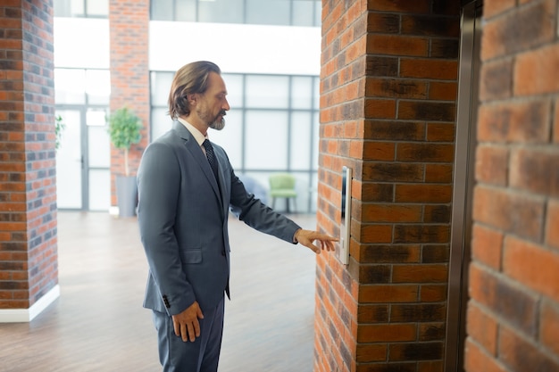 Grijsharige man. Grijsharige zakenman die een pak draagt dat op de lift wacht na een ontmoeting met partners