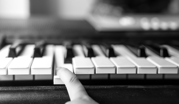 Grijswaardenopname van de vinger van een persoon die op de toets van een synthesizer drukt