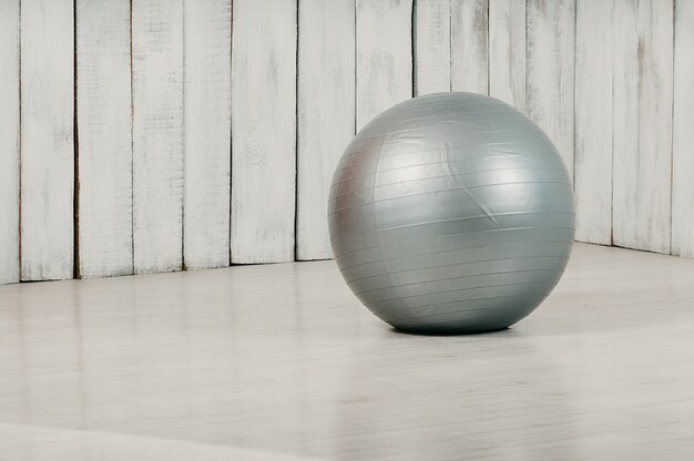 Grijze fitball in een sportschool, lichte vloer en achtergrond