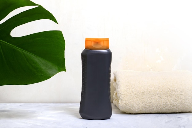 Grijze fles met shampoo en handdoek Concept voor persoonlijke hygiëne