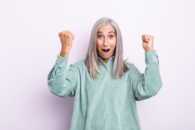 Grijze haarvrouw van middelbare leeftijd die een ongelooflijk succes viert als een winnaar, er opgewonden en blij uitziet en zegt: neem dat maar!