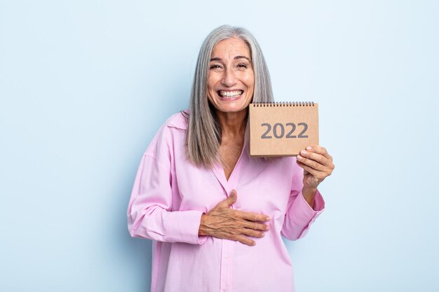 Grijze haarvrouw van middelbare leeftijd die hardop lacht om een of andere hilarische grap. 2022 kalenderconcept