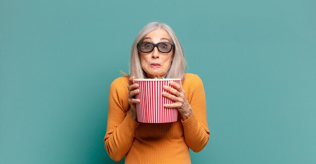 Grijze haren mooie vrouw met een emmer popcorn