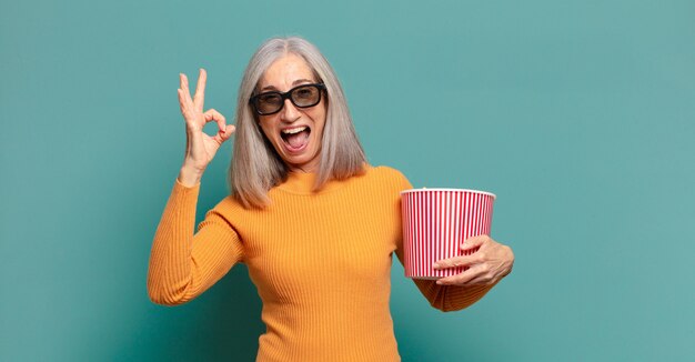 Grijze haren mooie vrouw met een emmer popcorn