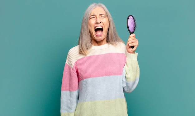 Grijze haren mooie vrouw met een haarborstel