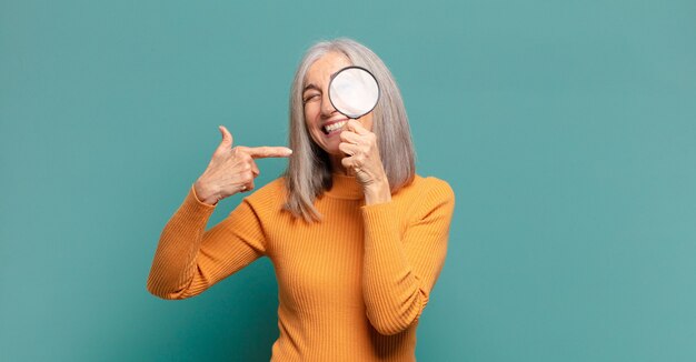 Grijze haren mooie vrouw met een vergrootglas