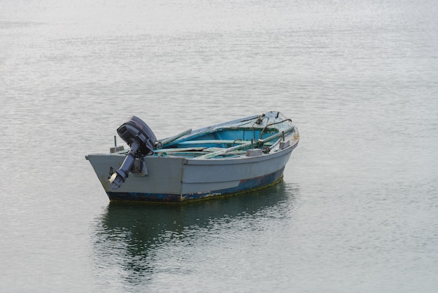 Grijze houten vissersmotorboot afgemeerd aan de kust