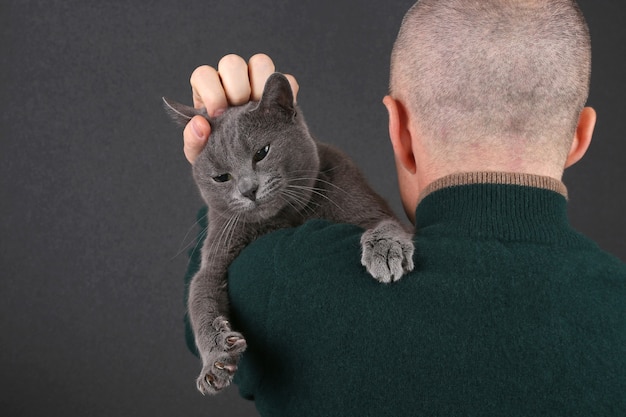 Grijze kat, zittend op de schouder van een man