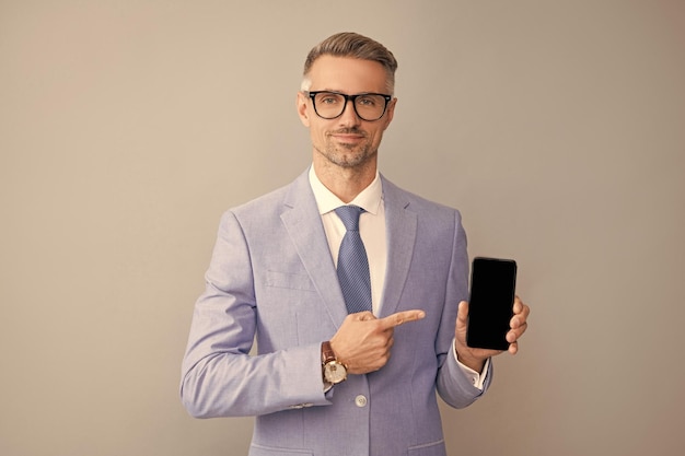Grijze man wijzende vinger op telefoon in pak en bril presentatie