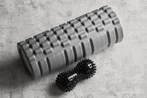 Grijze schuimroller en zwarte bal voor ontspannende spiermassage geïsoleerd op witte achtergrond Myofascial release concept Sport en herstel yoga selfmassagexA