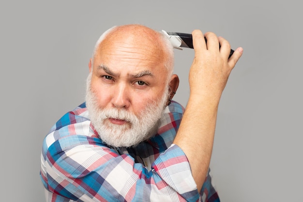 Grijze senior man haarknipsels. Kale oude man hairclipper, volwassen kaalheid en haaruitval concept.