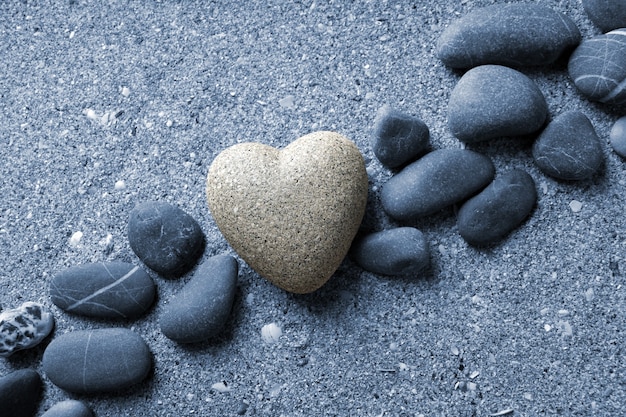 Grijze steen in vorm van hart, op zandoppervlak