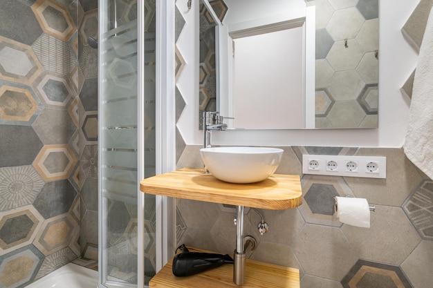 Grijze veelhoekige patroontegels in een badkamer met glazen douche en wastafelconcept van een stijlvol