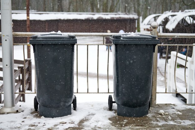 Grijze vuilnisbakken op straat in de winter. Openbare afvalcontainers aan de kant van de weg