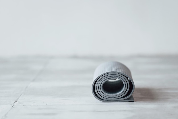 Grijze yogamat liggend op de houten vloer in de studio