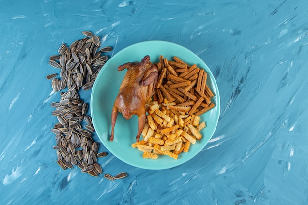 Grill and croutons on a plate next to pint, , on the blue surface.