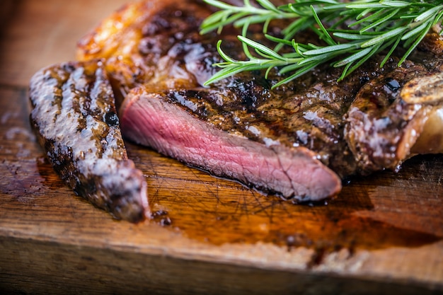 Grill juicy beef T-bone steak with salt pepper and rosemary.