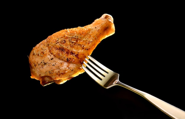 Grill roast bbq chicken leg on fork on black background