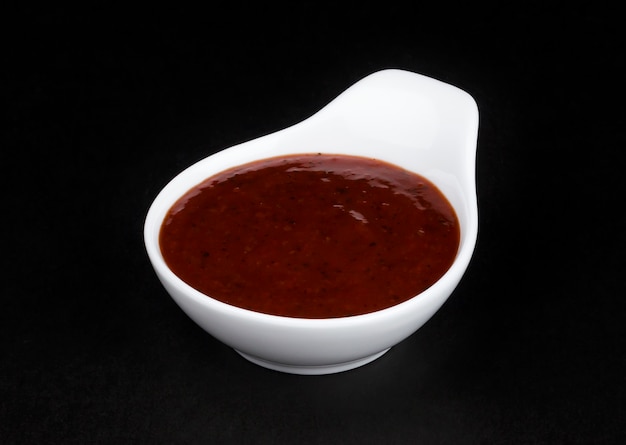 Photo grill sauce in white bowl isolated on black background