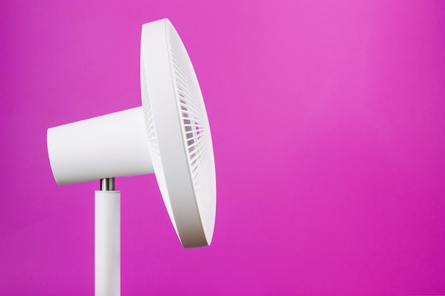 The grille and blades of the electric fan are white on a pink background.