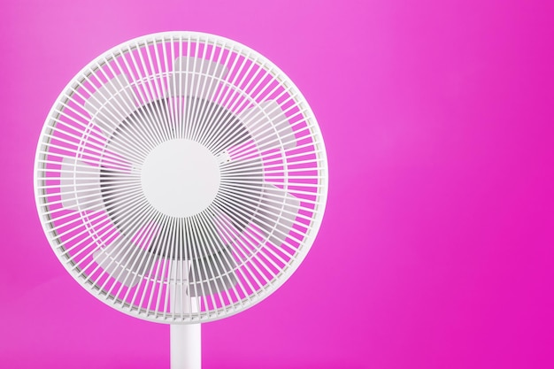 The grille and blades of the electric fan are white on a pink background.