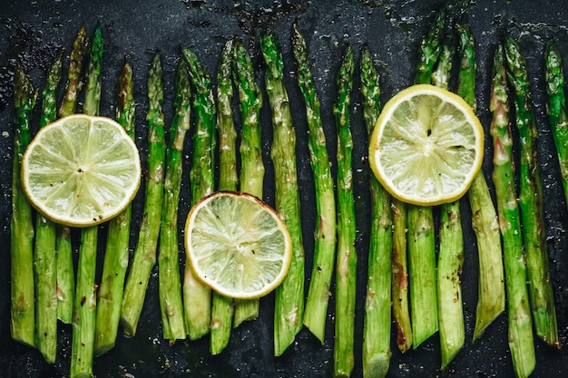 Grilled asparagus Baked or grilled green asparagus with lemon in black cast iron pan top view