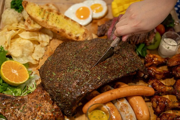 Grilled assorted meat with potato and dip sauces on wooden platter