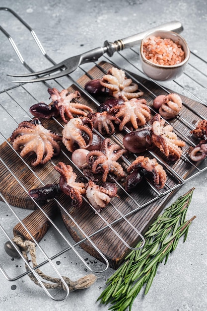 Grilled baby mini octopuses on a grill Gray background Top view