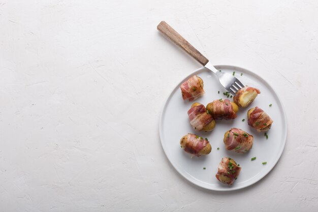 Grilled baby potato wrapped in bacon on the white plate