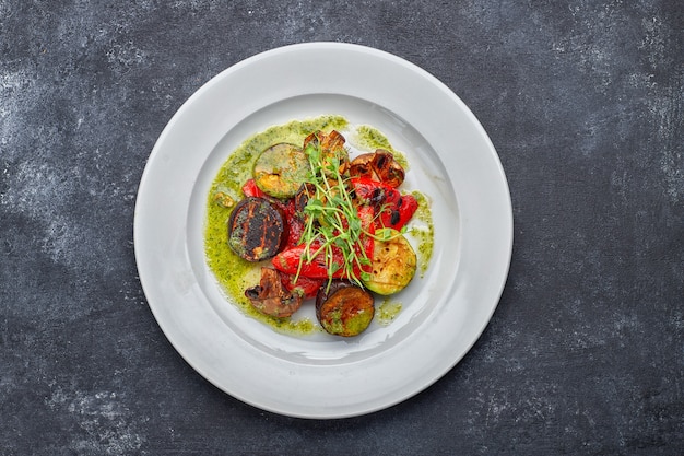 Grilled baked vegetables, eggplant, zucchini, bell pepper, champignon mushrooms, on a white plate