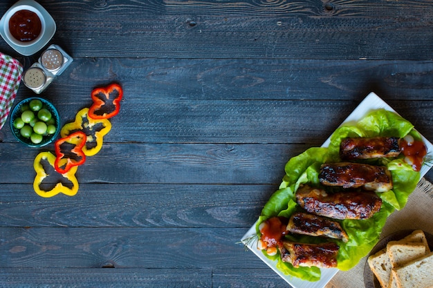 Grilled barbecue pork ribs with vegetables on a wooden background