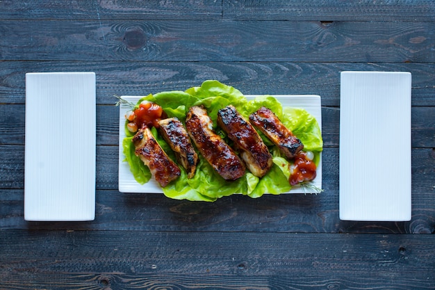 Grilled barbecue pork ribs with vegetables on a wooden table