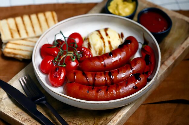 Grilled Bavarian sausages with mozzarella and cherry tomatoes in a plate with sauces