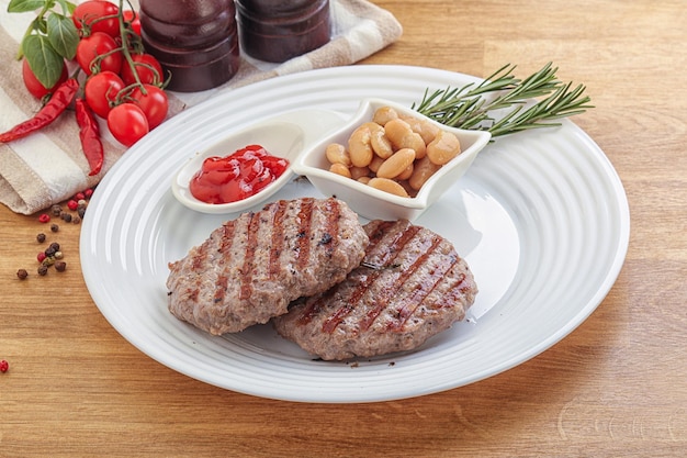 Grilled beef burger cutlet with sauce and beans