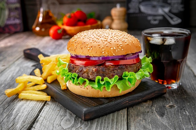 Grilled beef burger with tomatoes onions and fried potatoes