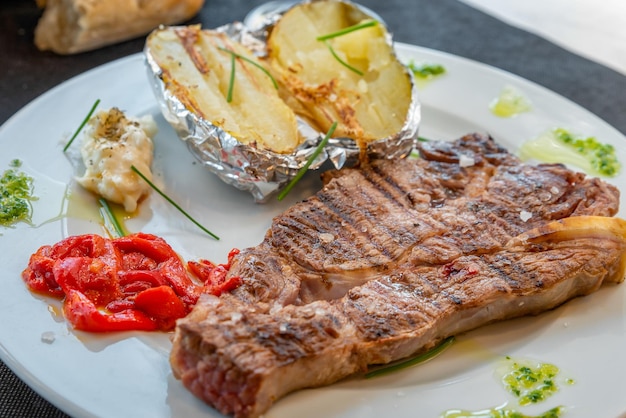 Grilled beef entrecote with potatoes on a white plate