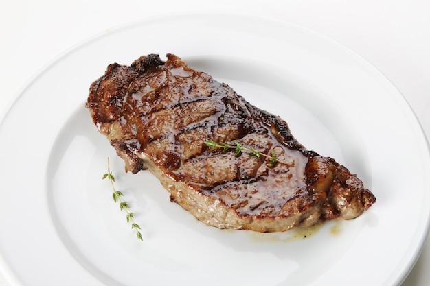 흰색 배경에 격리된 로즈마리를 곁들인 구운 쇠고기 등심 스테이크 고기