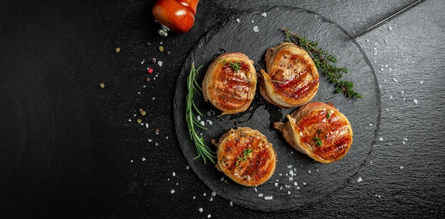 Grilled beef fillet steaks with herbs and spices Filet mignon served on a stone board. Long banner format, top view.