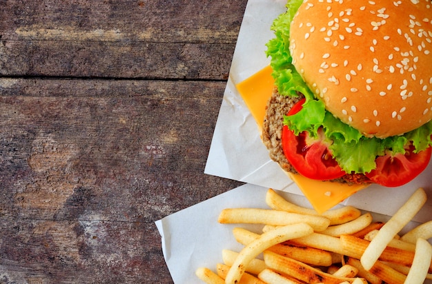 Grilled beef hamburger with vegetables on wood table, over light