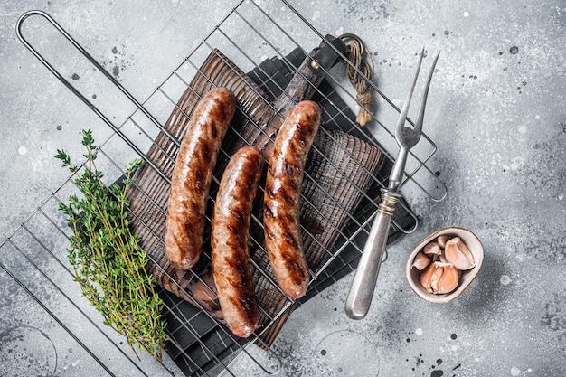 Grilled beef and lamb meat sausages with rosemary herbs on grill Gray background Top view