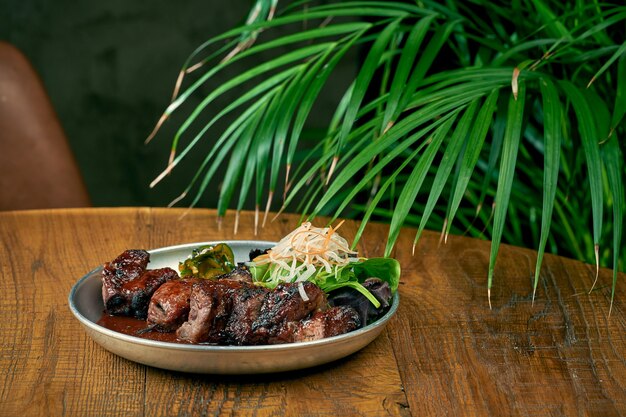 Grilled beef or pork with white barbecue sauce ponzu cucumbers and sauce in a plate on a wooden background