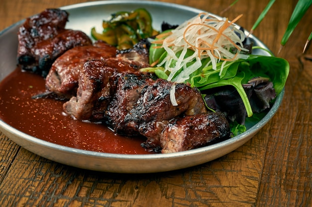 Grilled beef or pork with white barbecue sauce ponzu cucumbers and sauce in a plate on a wooden background