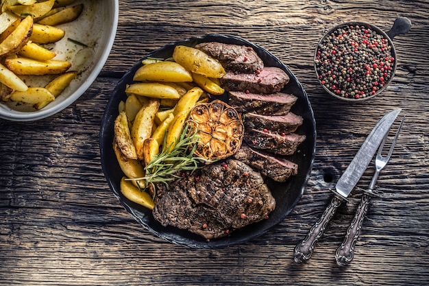 Grilled beef Rib Eye steak with garlic american potatoes rosemary salt and spices.