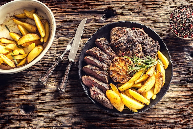 Grilled beef Rib Eye steak with garlic american potatoes rosemary salt and spices.