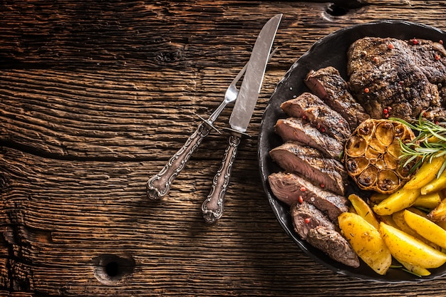 Grilled beef Rib Eye steak with garlic american potatoes rosemary salt and spices.