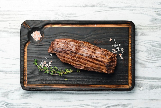 Grilled beef ribeye steak herbs and spices Top view with space for copying text On a wooden background